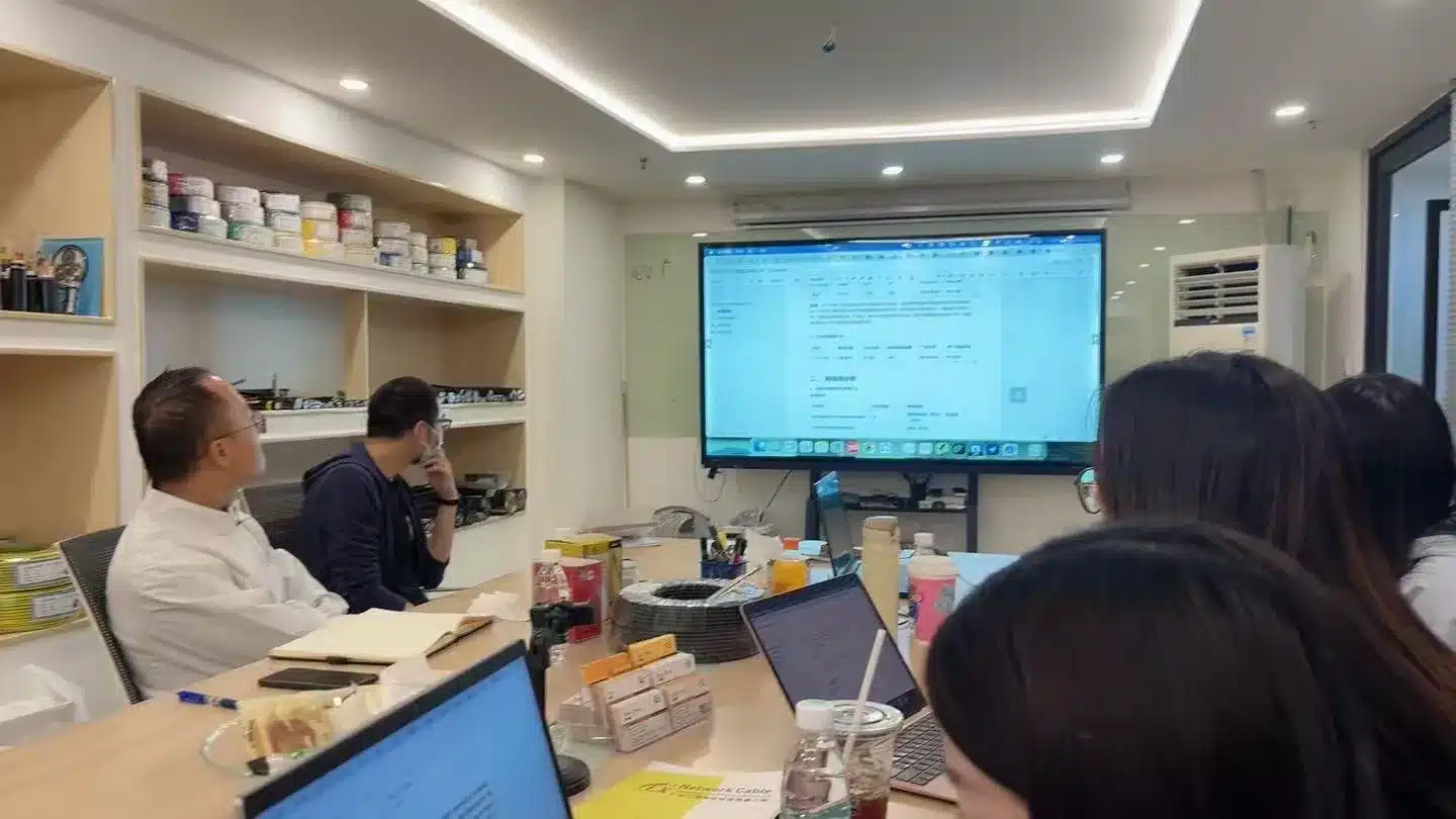 Infility team in a client strategy session, reviewing Google campaign dashboards on a large screen while participants work on laptops and take notes, illustrating hands-on campaign setup and optimization. This scene highlights Infility’s B2B Google Ads代运营 service and full-funnel approach to driving high-quality export inquiries.