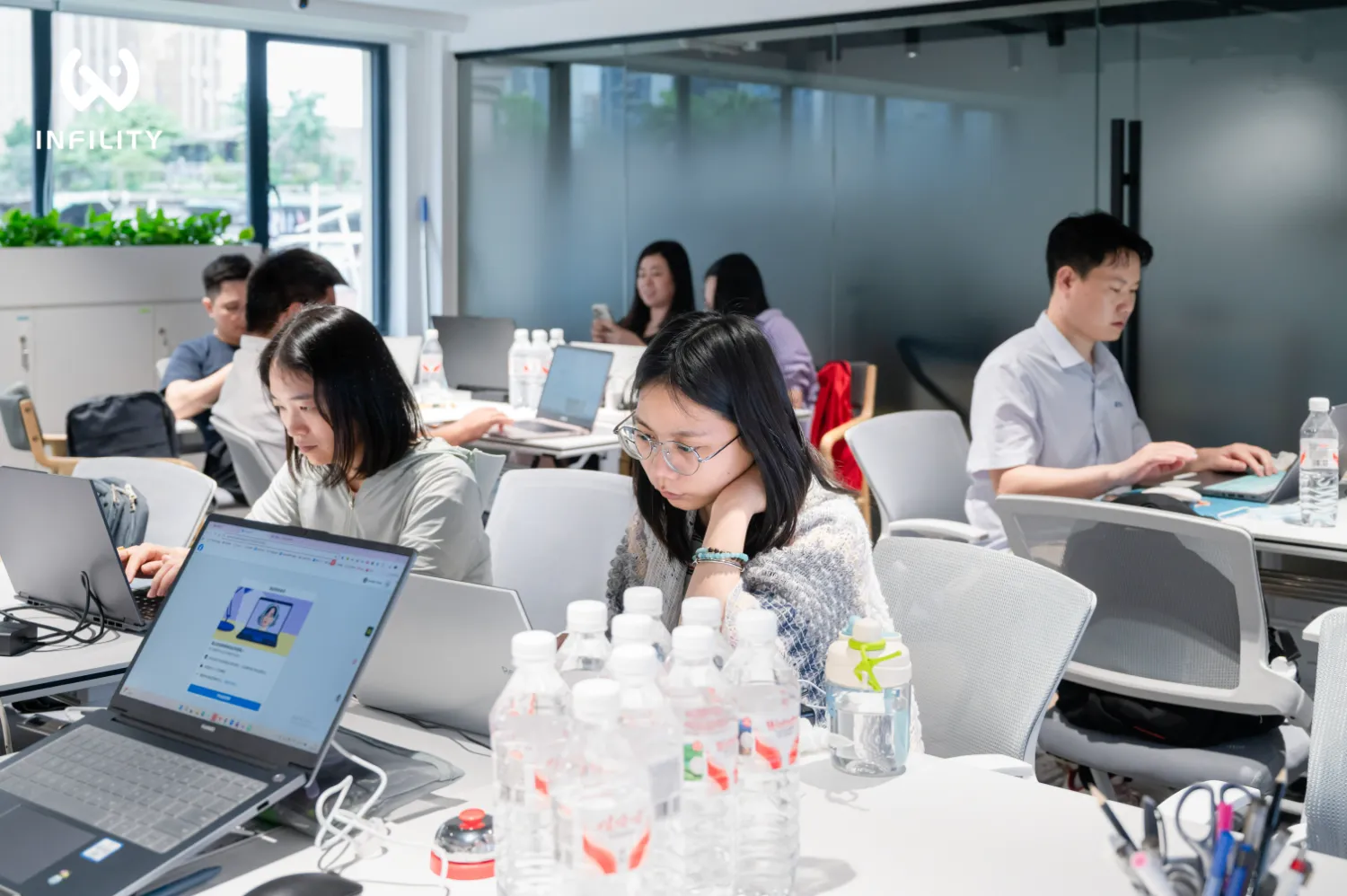 外贸团队在开放式办公区用笔记本电脑整理关键词分层与页面排期台账