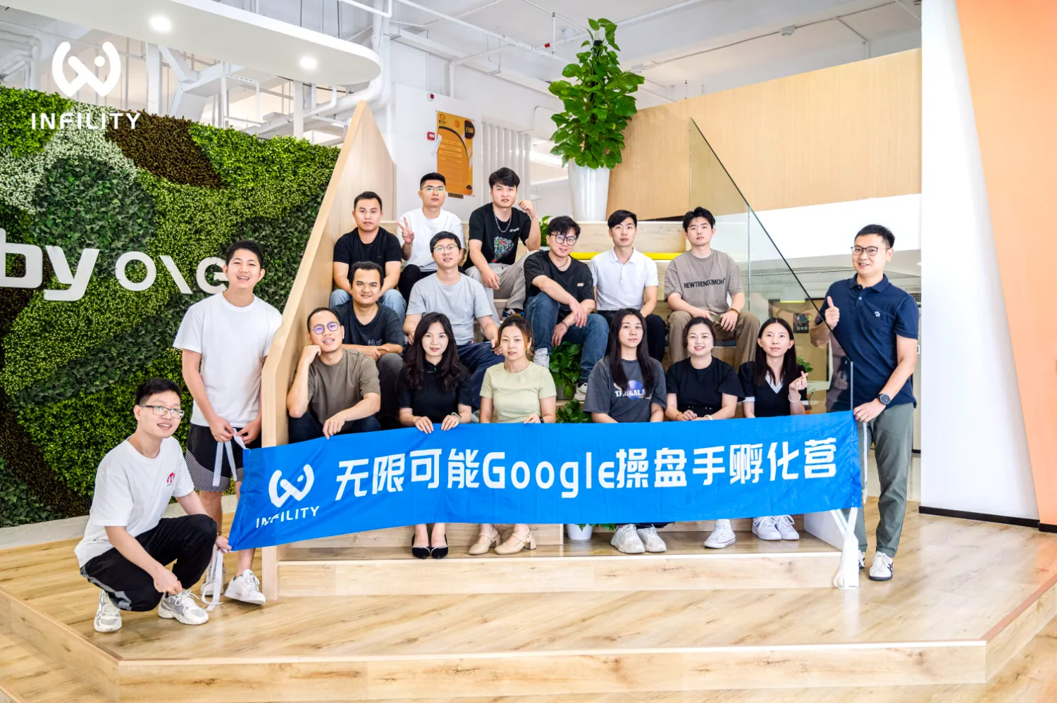 一群学员手持印有“无限可能Google操盘手孵化营”字样的蓝色横幅在室内合影