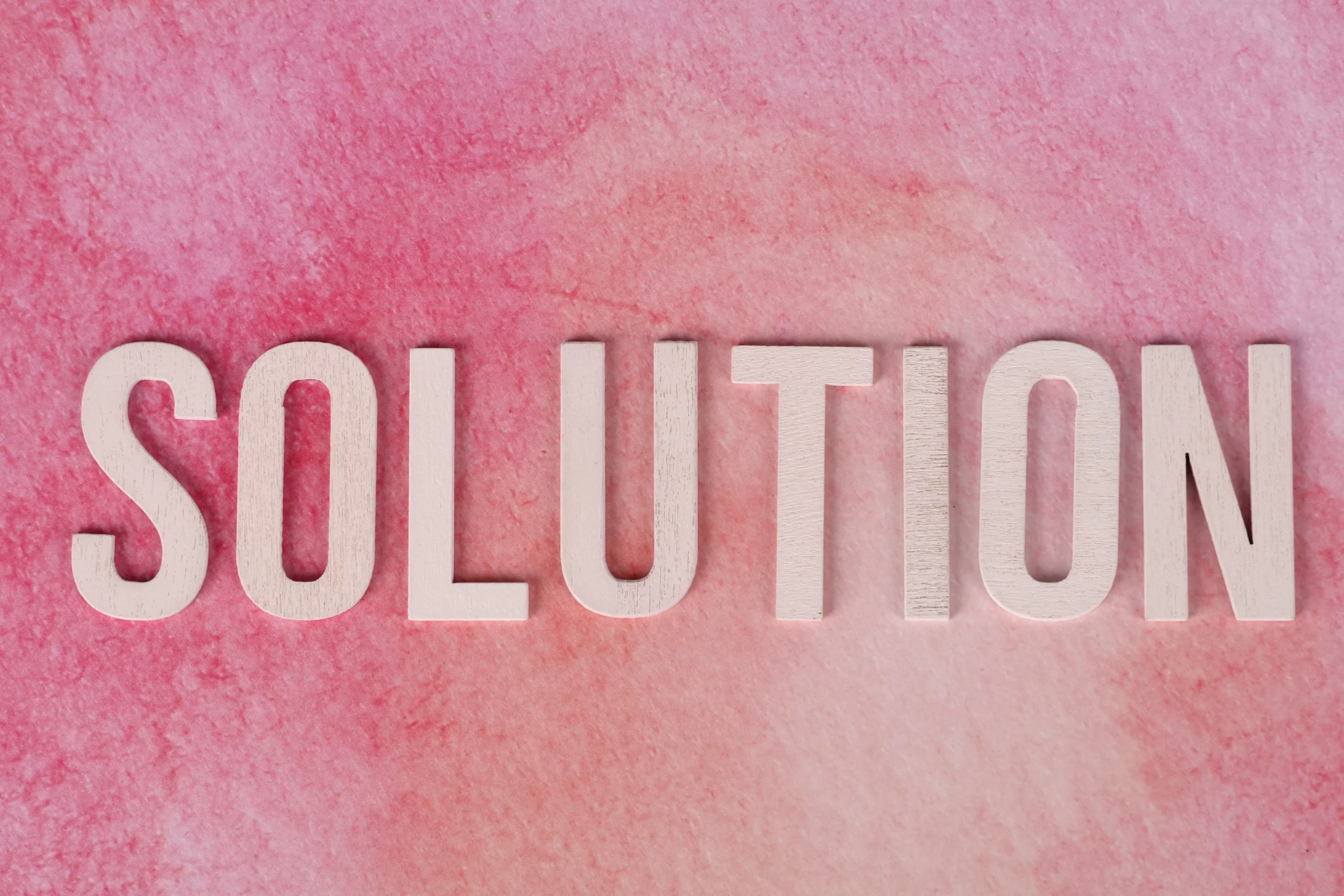 Wooden letters spelling "SOLUTION" on a pink textured backdrop, symbolizing Infility’s brand and commitment to conversion-driven WordPress independent site and landing page design. This image represents our service offering 批量导入类目: 网站转化与页面设计, highlighting conversion optimization and page design for B2B export businesses.