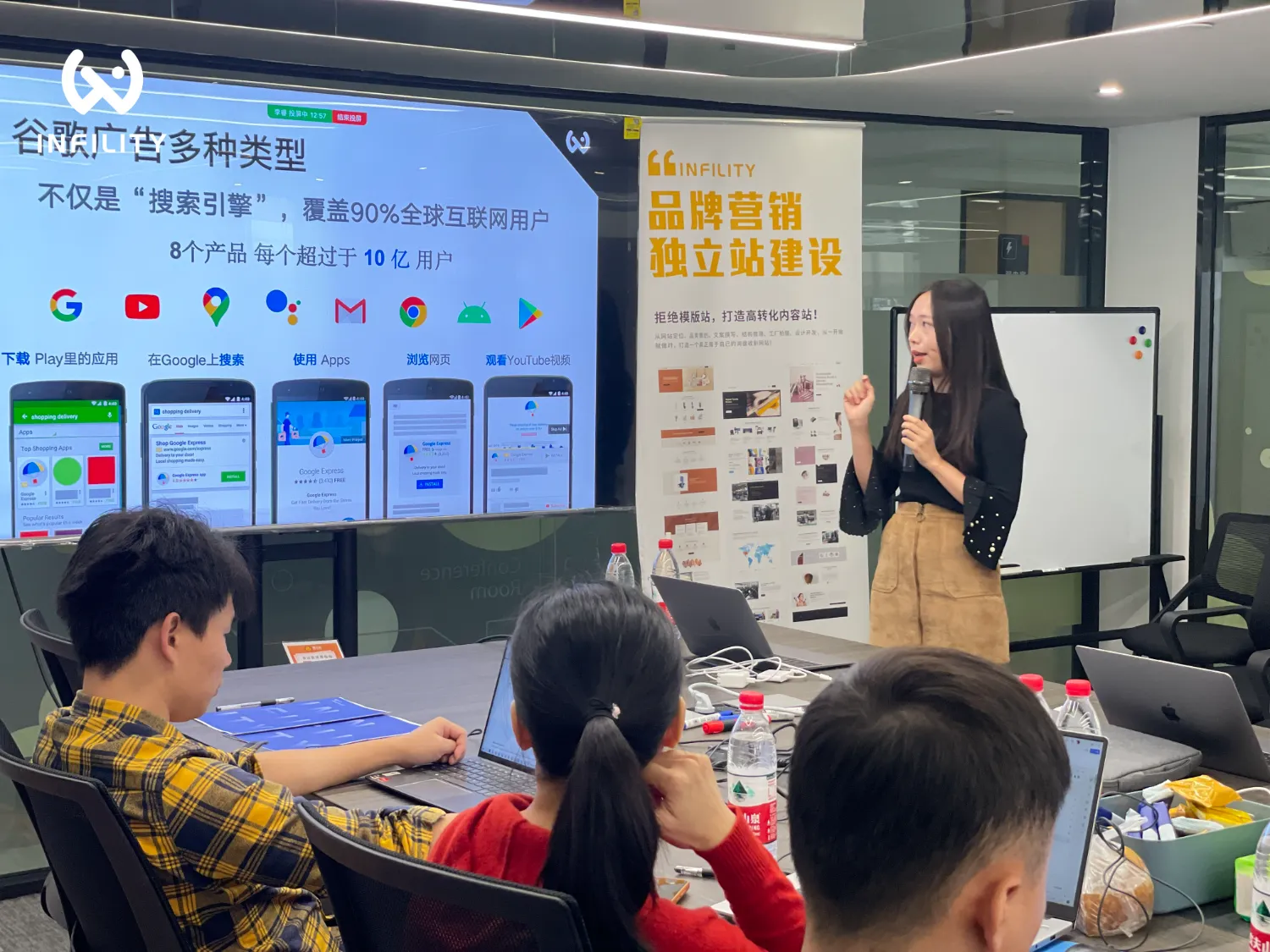 讲师在会议室讲解谷歌广告多种类型及品牌营销独立站建设，台下听众正在听讲。